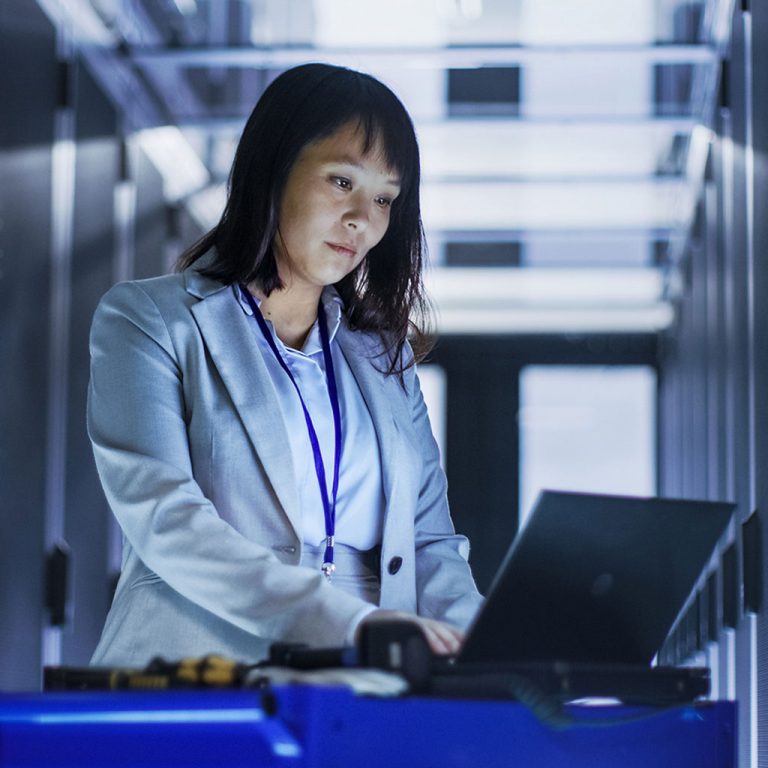 Woman on laptop in server room